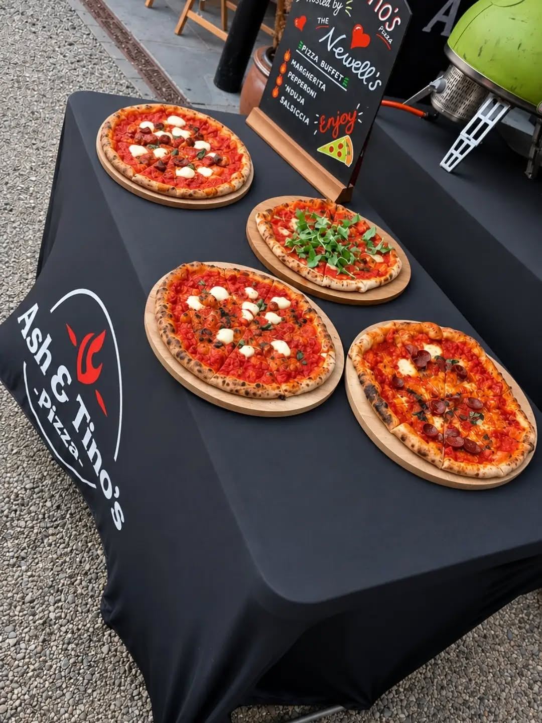 Four pizzas laid out on branded serving boards at a pizza buffet